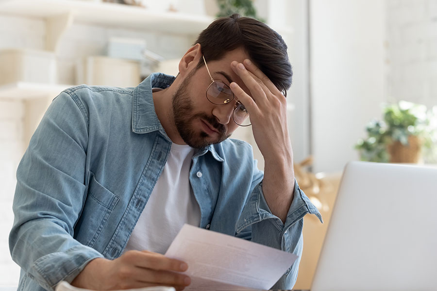 A man in a blue and white shirt holding his head disappointedly and holding a piece of paper with a false estimate from a power washing company in Springfield, IL.