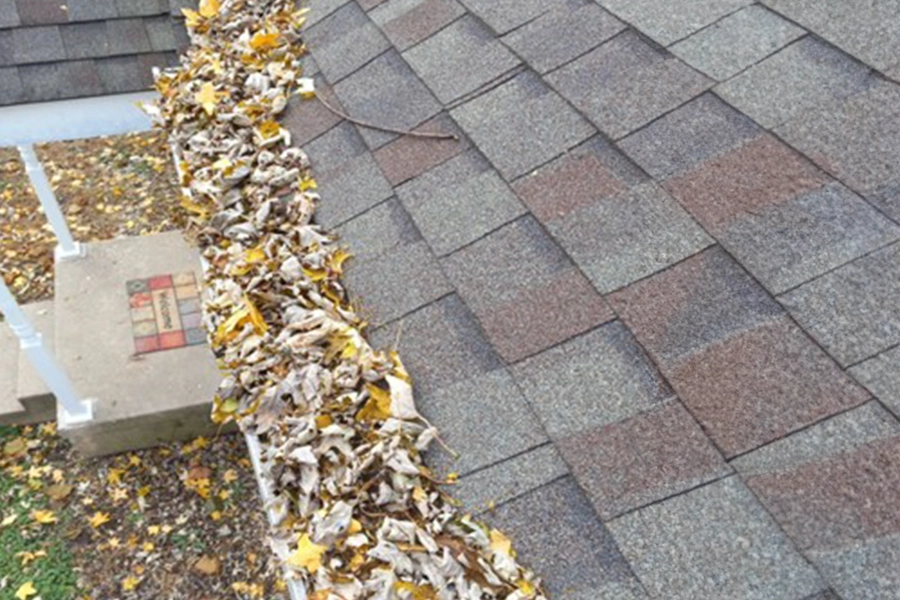 This is a photo of a Petersburg Power Washing customer’s house in Springfield, IL on a fall day showing a roof with leaves in the gutters.